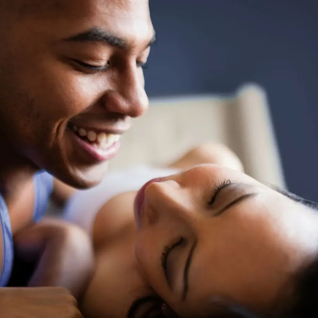 Couple smiling closely together in bed