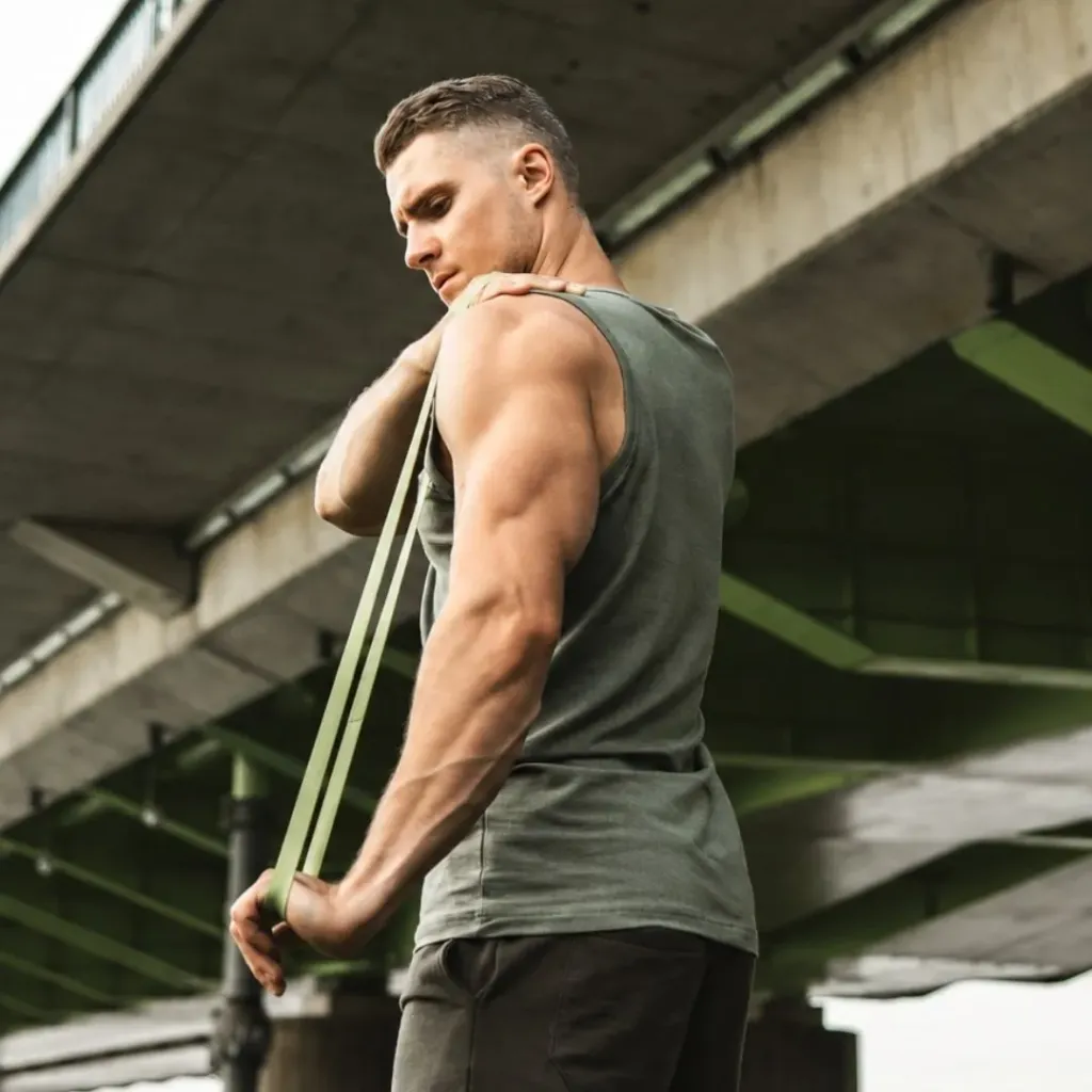 Man performing a resistance band exercise, muscular back visible